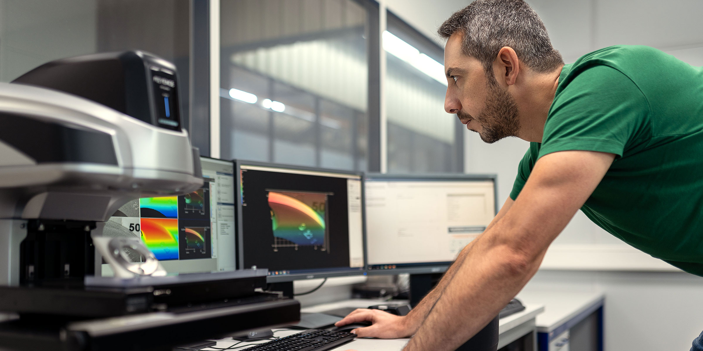 Ein Mitarbeiter der Qualitätsabteilung inspiziert ein Präzisionsbauteil mithilfe eines digitalen Messprojektors.