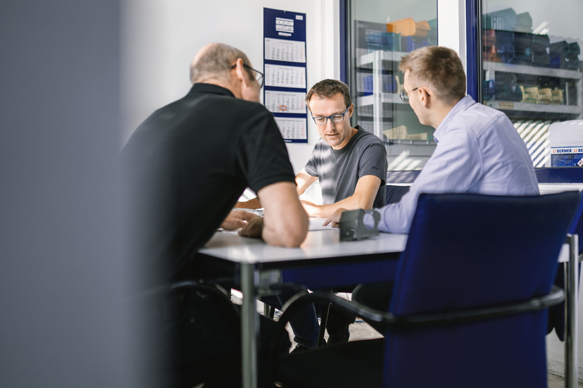 Mitarbeiter im technischen Umfeld bei einer gemeinsamen Besprechung am Arbeitsplatz.